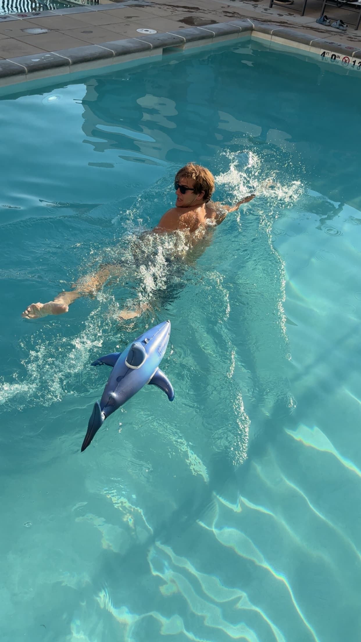 Blake swimming in a pool, chased by an inflatable shark